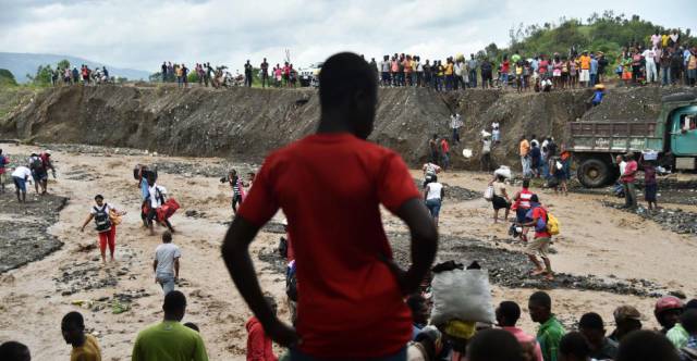 Haitianos cruzan el río La Digue en Petit Goave que se desbordó por las fuertes lluvias del huracán.
