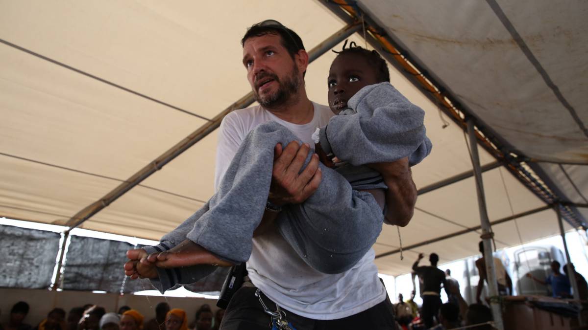 Inego, logista del Dignity I, lleva en brazos a una niña a la clínica de la nave.