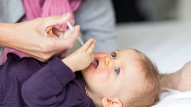 Una madre da un medicamento a su bebé.