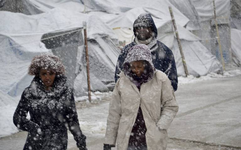 Refugiados caminan bajo la nieve en el campamento de Moria, en Lesbos. Refugiados caminan bajo la nieve en el campamento de Moria, en Lesbos.
