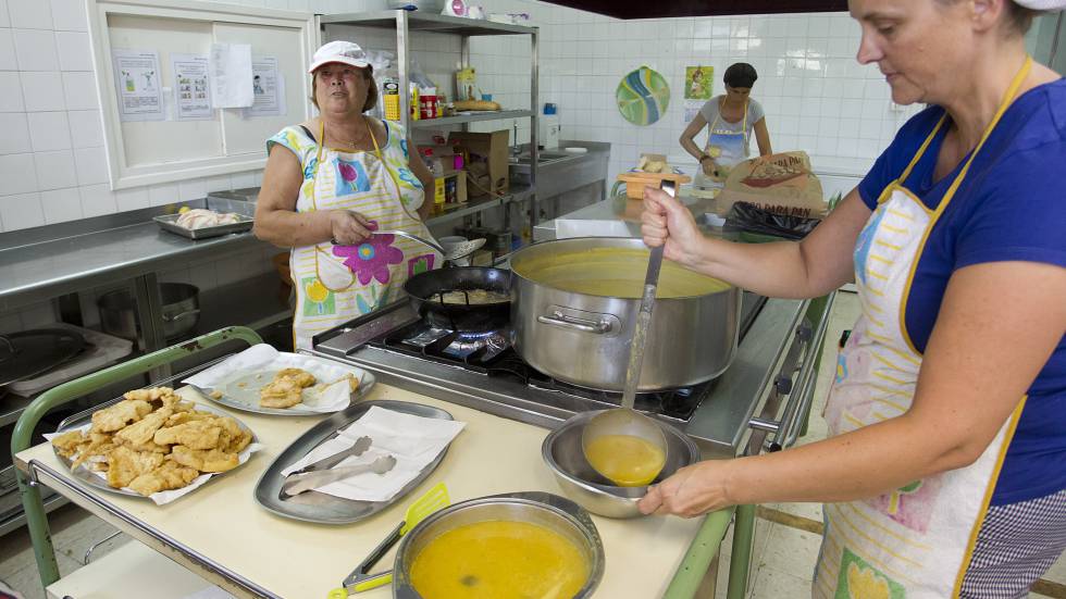 Dos voluntarias preparan sopa de verduras en un campamento de verano para niños sin recursos.