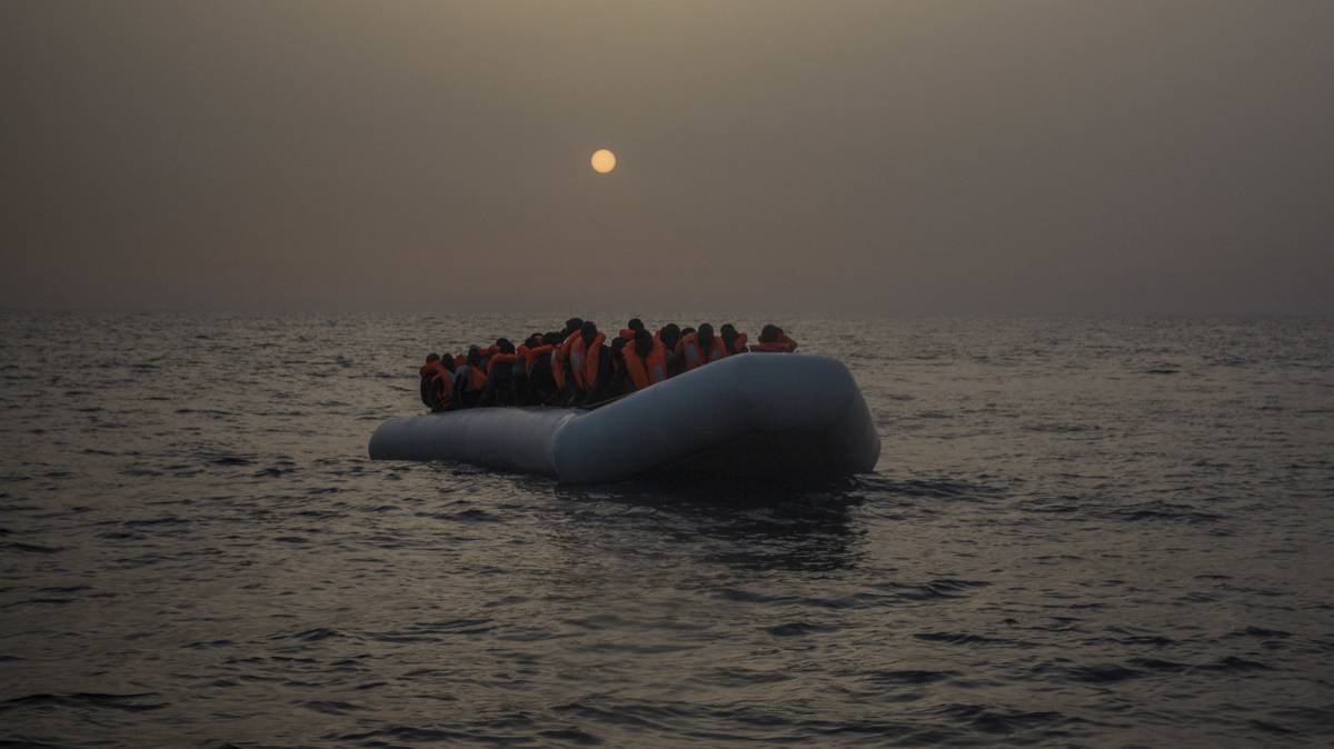 Varios refrugiados y migrantes esperan, abordo de un un bote de goma a la deriva, a ser asistidos por miembros de la ONG española Proactiva Open Arms.