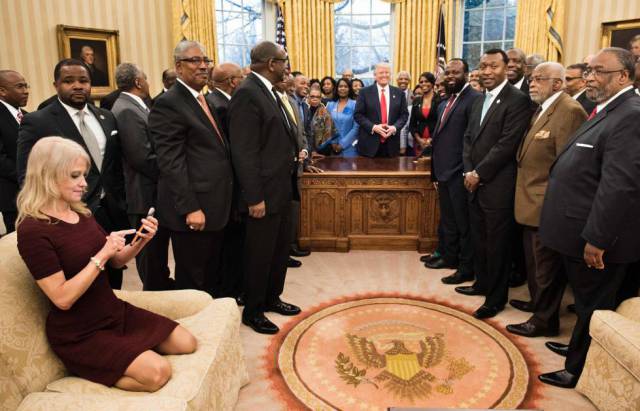 Kellyanne Conway mira su teléfono sentada de manera informal en uno de los sofás del Despacho Oval.