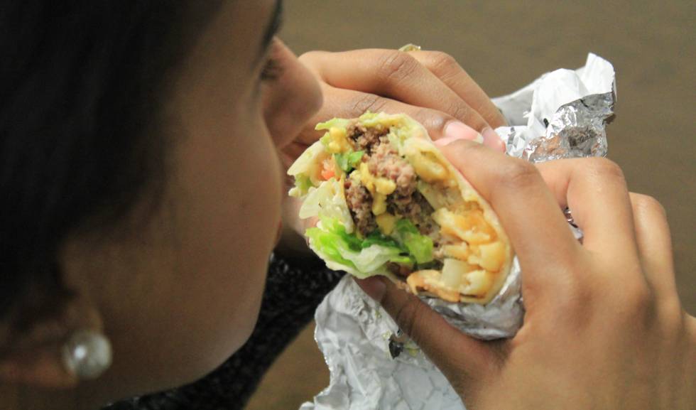 Una persona comiendo un "burgrito", una combinación de burrito mexicano y hamburguesa.