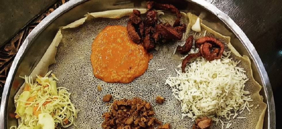 Shiro y otros guisos de legumbres, carne y arroz sobre una injera.
