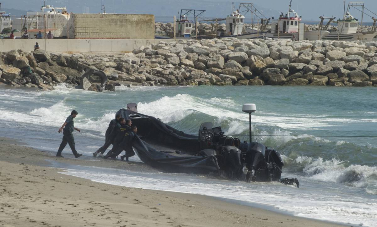Guardias civiles empujan una lancha utilizada por los narcos en el Estrecho.