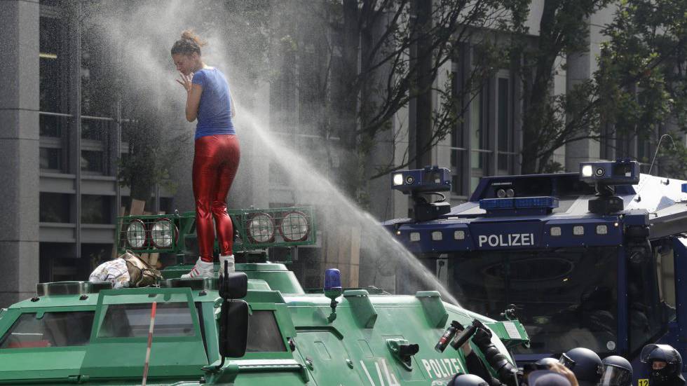 Una mujer es rociada con pimienta por la policía después de subirse a un vehículo, durante las protestas en la primera jornada de la cumbre del G20 en Hamburgo, Alemania.