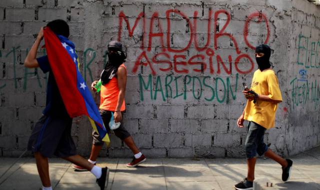 Manifestantes pasan junto a un graffiti, durante la huelga general.