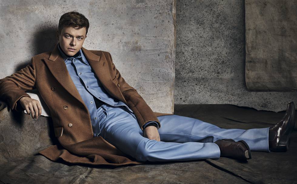 DeHaan lleva abrigo camel de cachemir, cuello vuelto negro 205, camisa y vaquero de cuero y botas ‘chelsea’ con puntera de plata, todo, Calvin Klein 205W39NYC.
