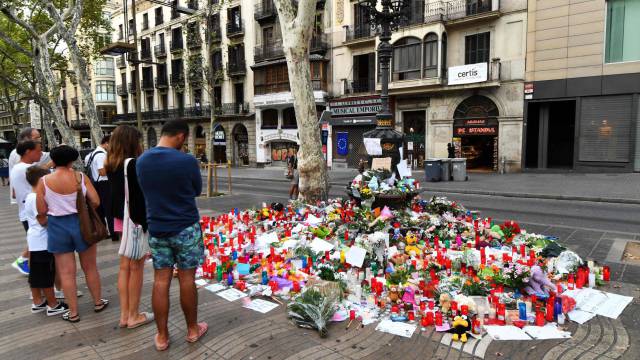 Varias personas observan las velas y flores por las víctimas en La Rambla.