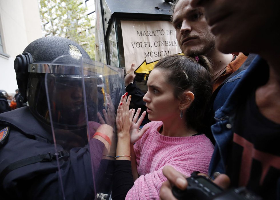La policía evita con sus escudos que la gente se acerque a una mesa de votación en Barcelona.