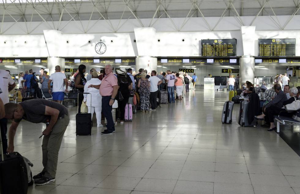 Pasajeros reubicados de la aerolínea británica Monarch, con destino a Birminghan, hacen cola en el aeropuerto de Gran Canaria para facturar en un vuelo de los denominados de