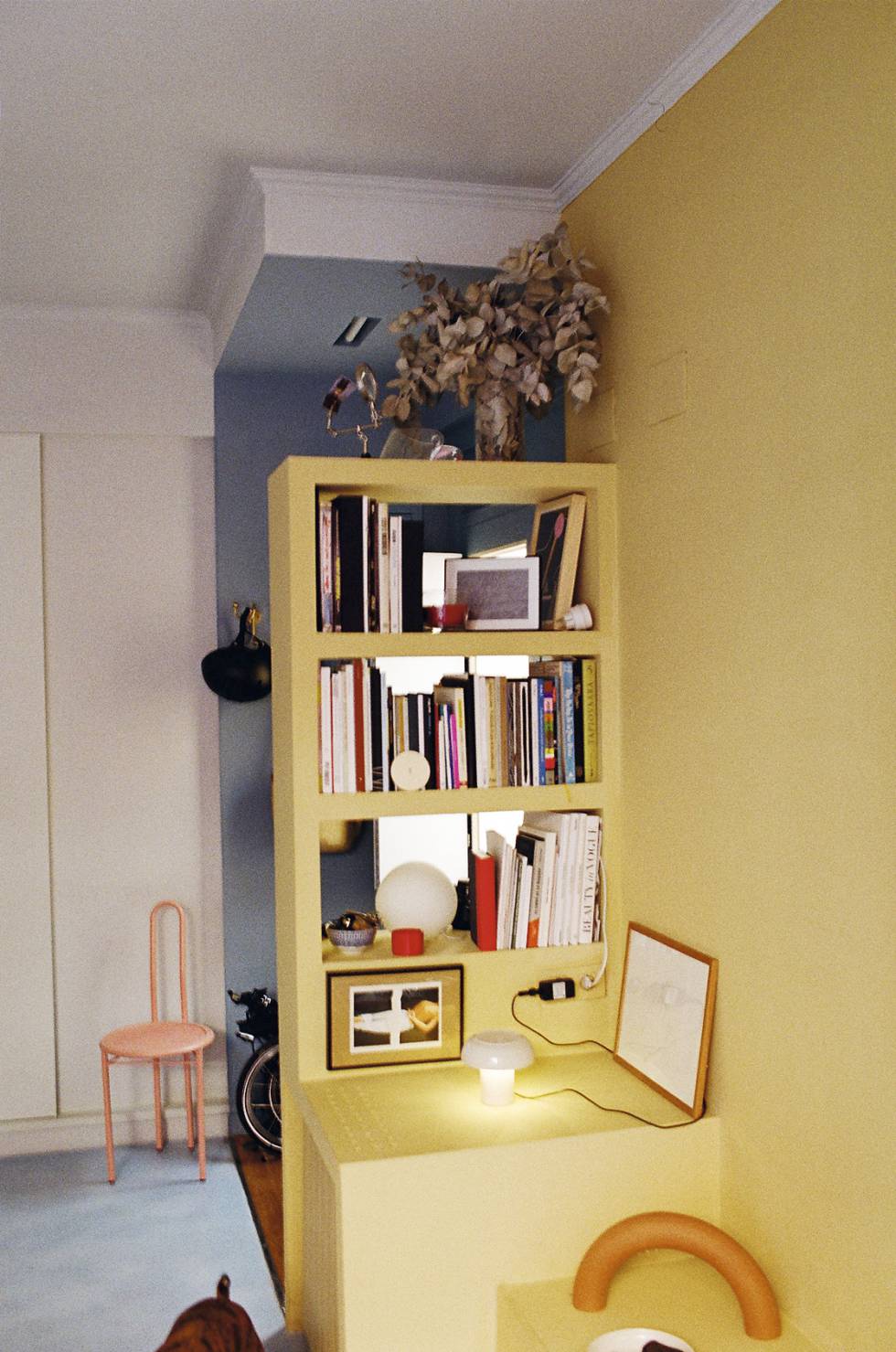 El módulo de pladur amarillo articula gran parte de la vivienda. Las dos lámparas también son obra de Enrich. Al fondo, la silla Patio en su obligatorio color rosa.