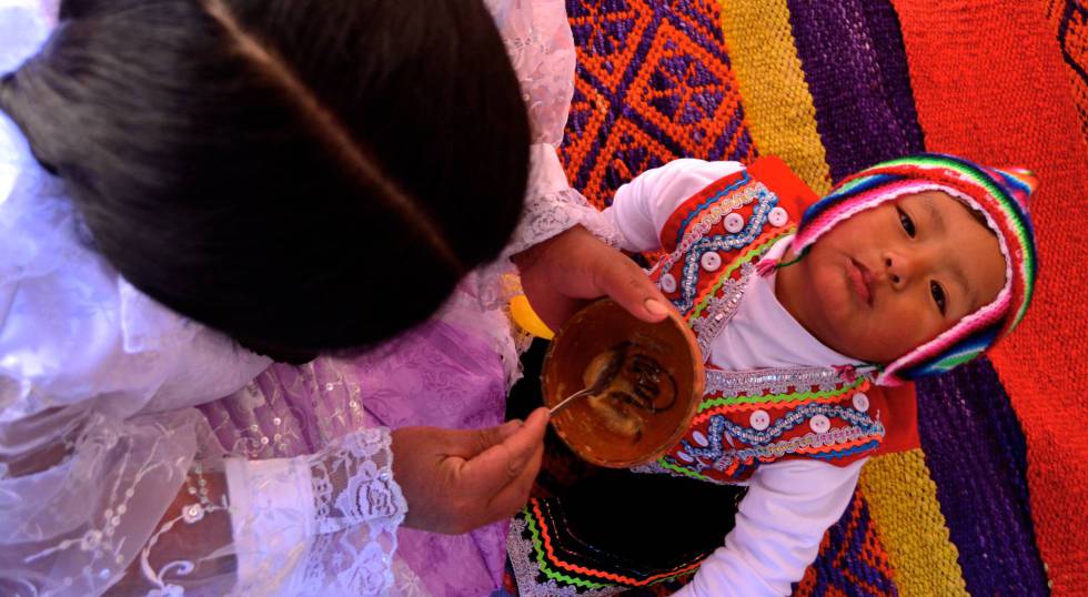 Lidia Dueñas le da de comer a su hijo en el rincón de juegos que tiene en su casa en Lucre (Quispicanchi, Cuzco, Perú).