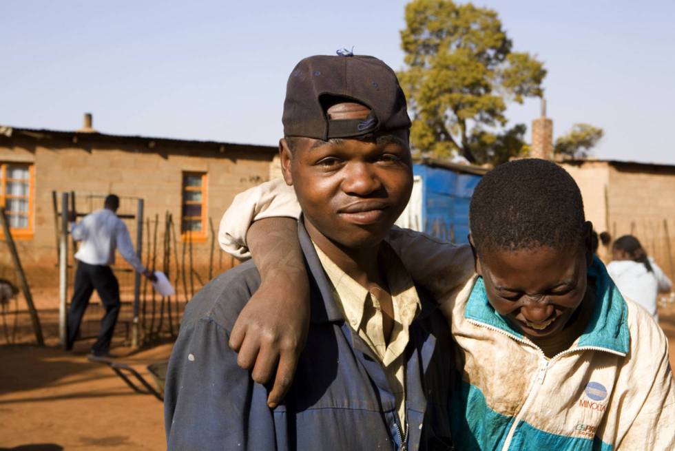 Dos amigos se ríen en el asentamiento temporal en Bapsfontein, a 80 kilómetros de Johannesburgo (Sudáfrica).