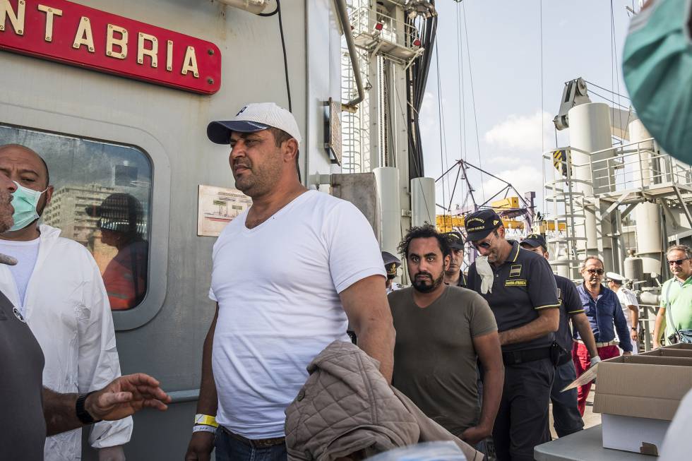 Dos de los migrantes, señalados como “personas de interés”, bajan del buque escoltados por agentes italianos en Palermo.