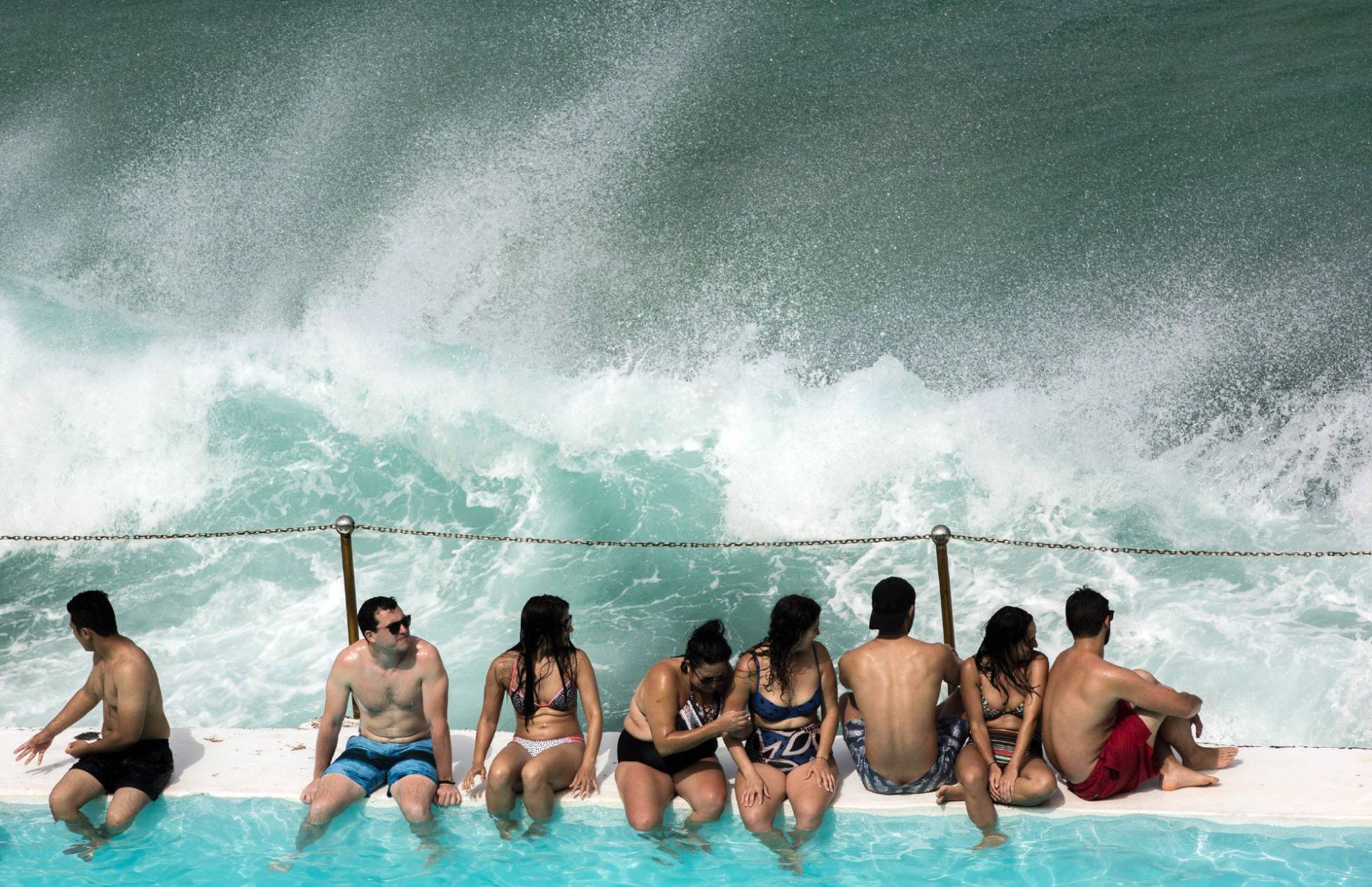 Varias personas sentadas en el borde de una piscina en Sídney (Australia).