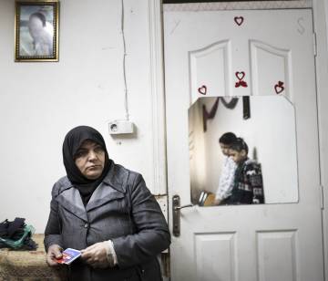 Nahla, en su casa con sus dos hijos pequeños. El retrato en la pared es de su difunto marido.