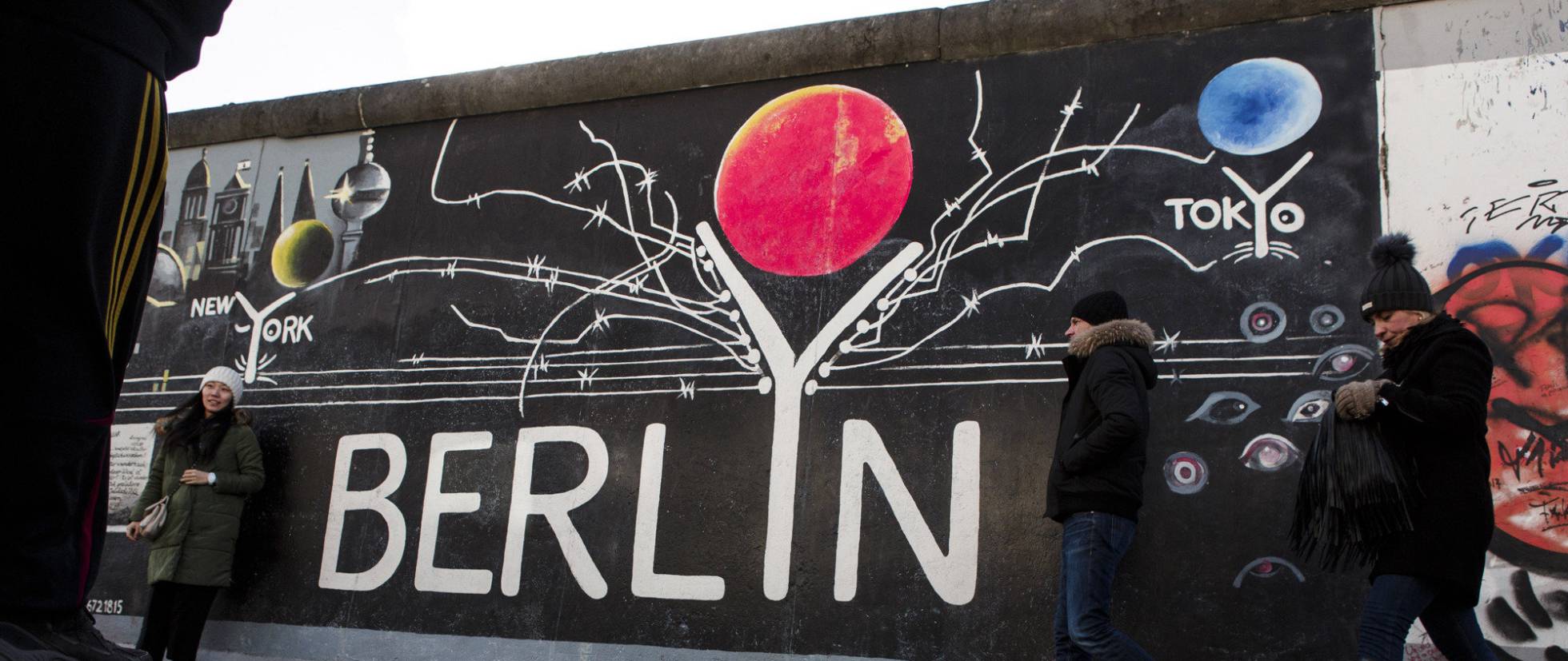 BERLIN, GERMANY - FEBRUARY 05: Vsitor passing a painting at the Berlin Wall at the East Side Gallery on February 5, 2018 in Berlin, Germany. Today tem been 10,316 days since the Berlin Wall officially fell, the same number of days that it stood between 1961 and 1989. The Berlin Wall, built by the communist authorities of East Germany, divided capitalist West Berlin from communist East Berlin and came to symbolize the Cold War between the western Allies, led by the United States, and the Eastern Bloc, led by the Soviet Union. (Photo by Carsten KoallGetty Images)