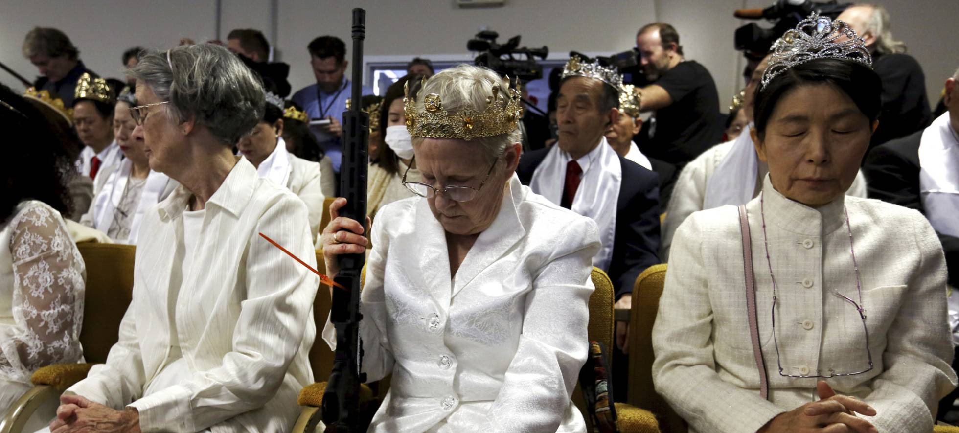 A woman wears a crown and holds an unloaded weapon as she bows her head during services at the World Peace and Unification Sanctuary, Wednesday Feb. 28, 2018, in Newfoundland, Pa. Worshippers clutching AR-15 rifles participated in a commitment ceremony at the Pennsylvania-based church.The event Wednesday morning led a nearby school to cancel classes for the day.The church's leader, the Rev. Sean Moon, said in a prayer that God gave people the right to bear arms. (AP PhotoJacqueline Larma)