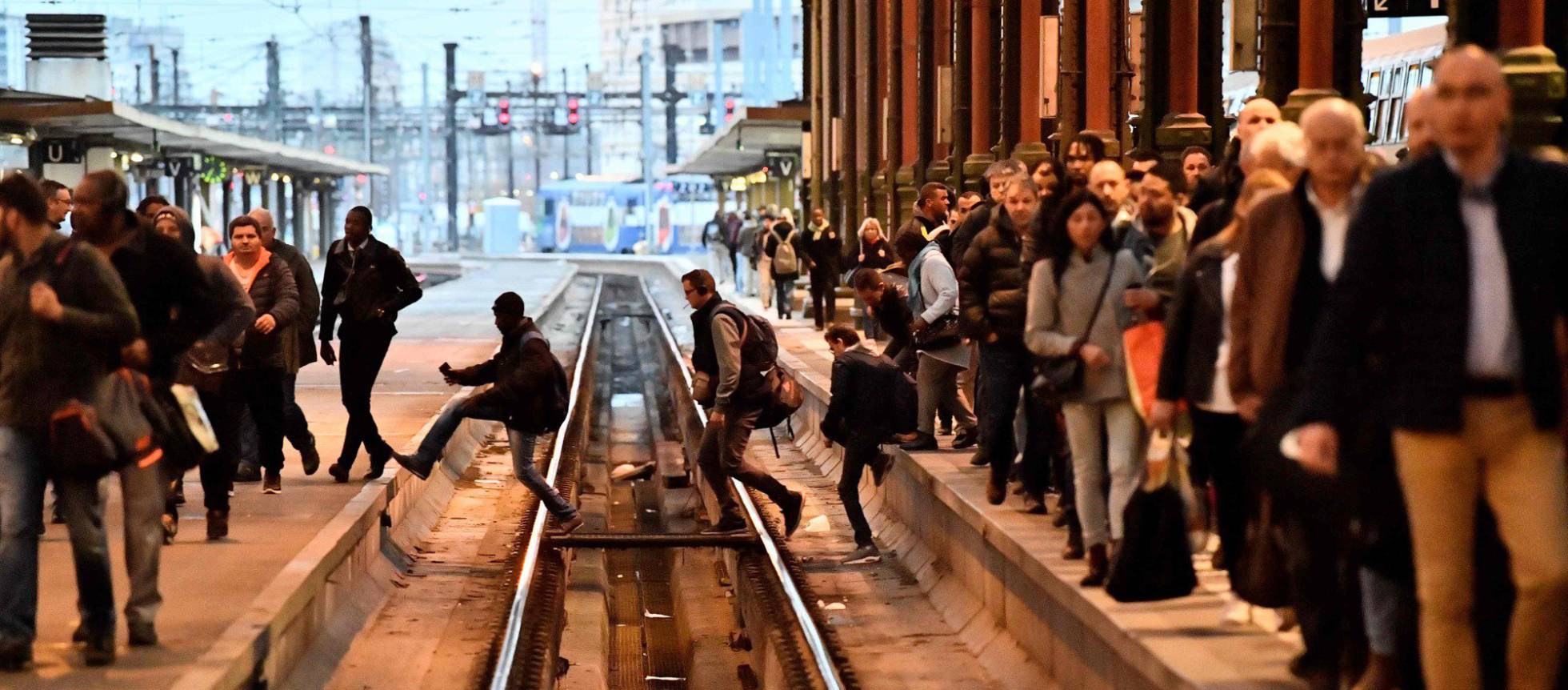 Passageiros cruzam as vias do trem em uma estação de Paris (França).