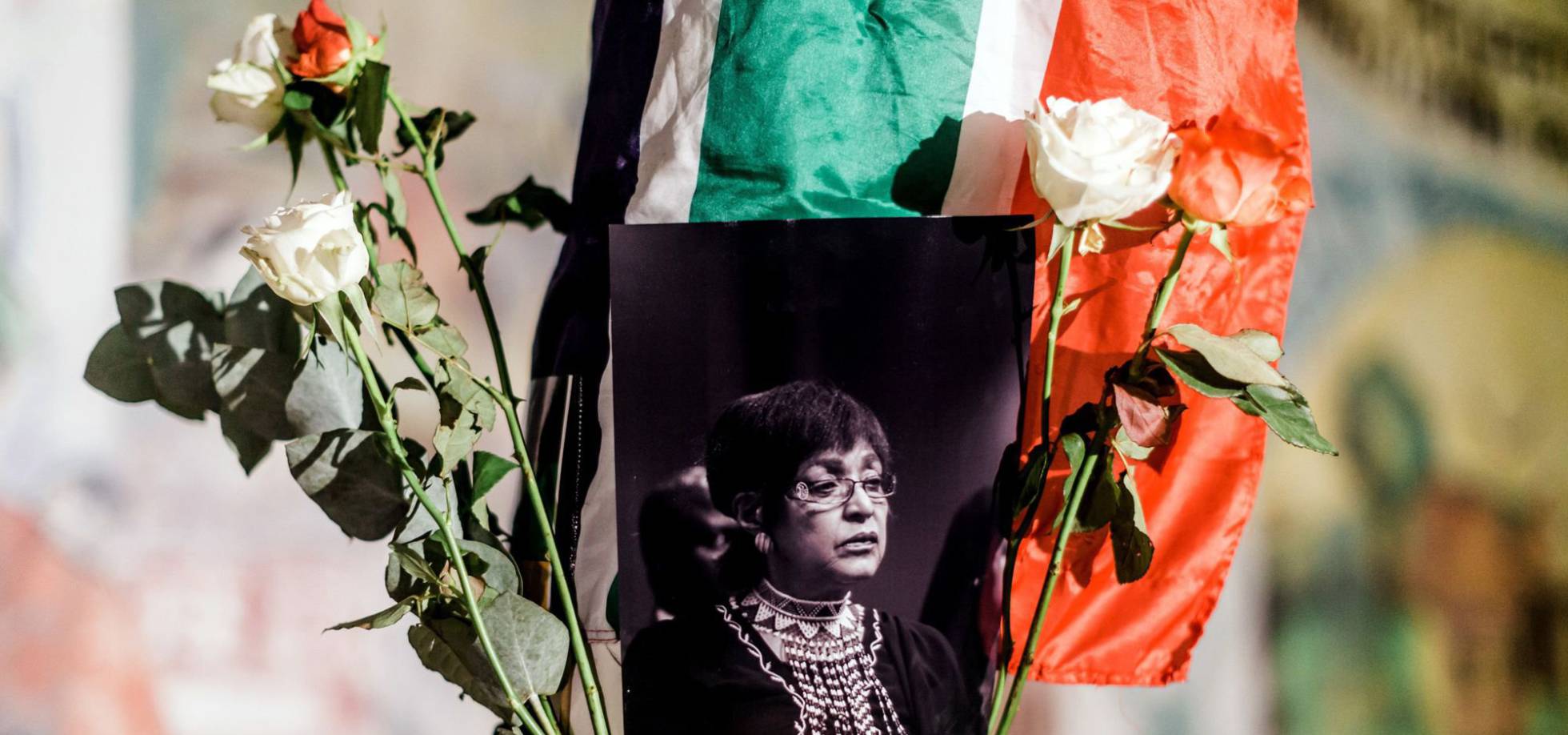 TOPSHOT - A black and white photograph of the late Winnie Madikizela-Mandela is surrounded by the South African and African National Congress (ANC) flags on a pole at the Old Durban Prison's Human Rights wall as South Africans gather to pay respect to the late high-profile anti-apartheid activist during a candle vigil in Durban on April 2, 2018. Winnie Mandela, the former wife of South African anti-apartheid icon Nelson Mandela, died on April 2, 2018, aged 81, triggering an outpouring of tributes to one of the country's defining and most divisive figures. AFP PHOTO Rajesh JANTILAL