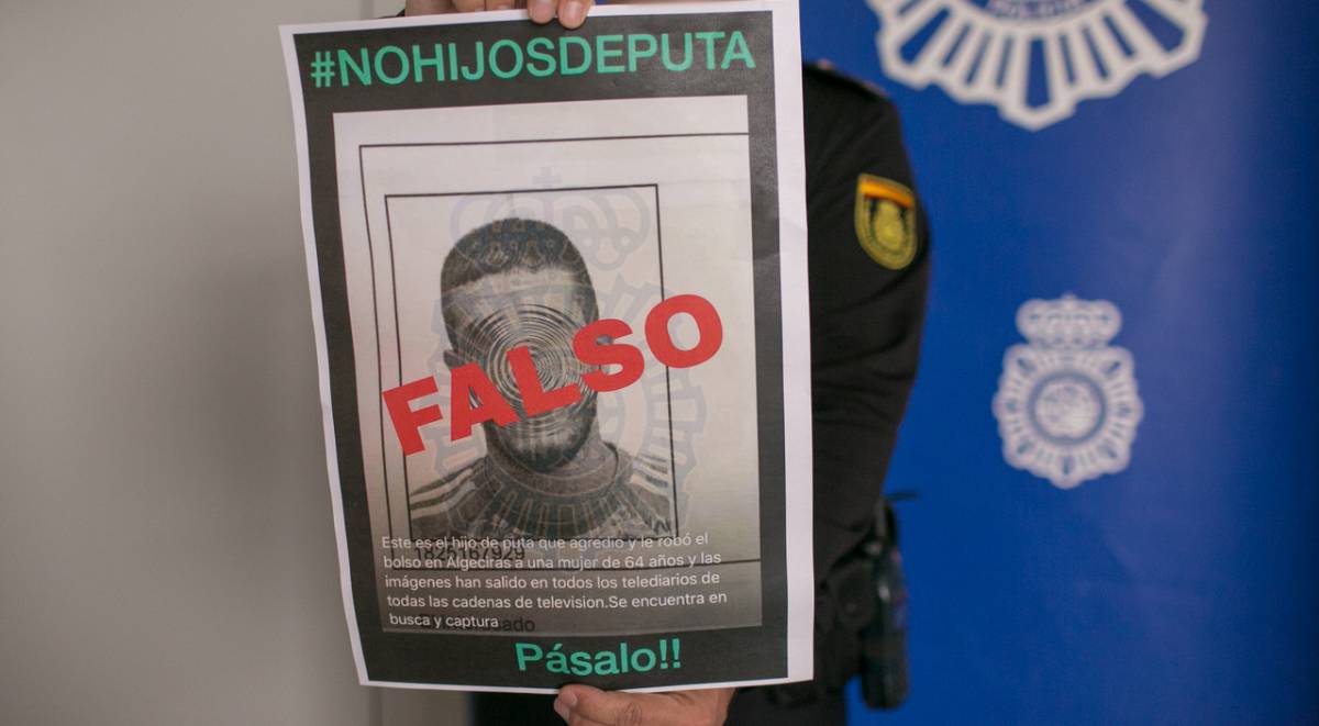 Un policía, con un cartel desmintiendo un bulo.