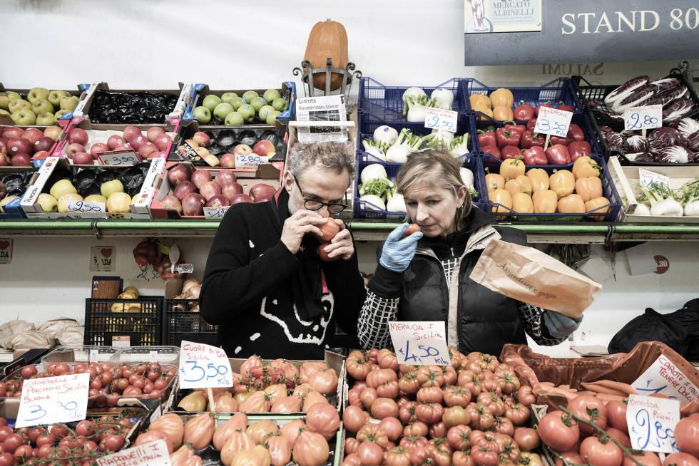 Bottura huele el aroma de un tomate en una frutería del mercado tradicional Albinelli.