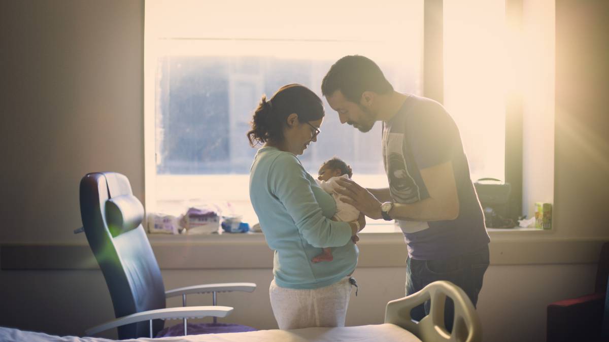Dos padres miran a su recién nacido.
