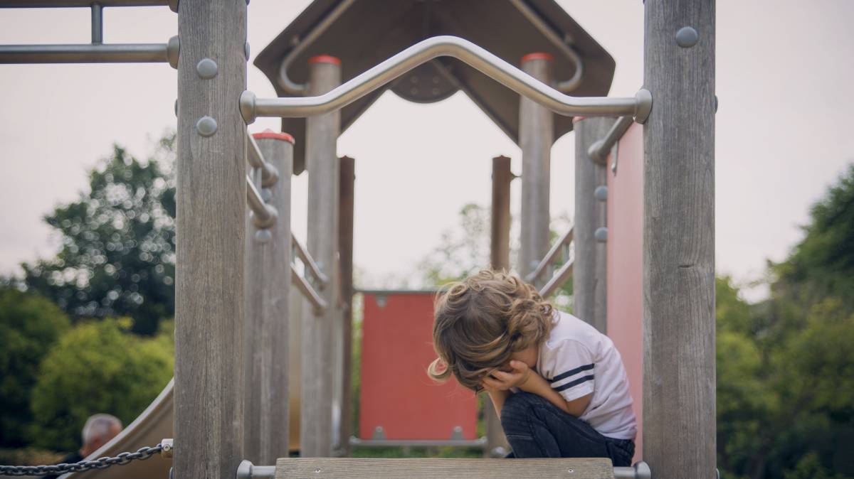 Un niño llora en un columpio.