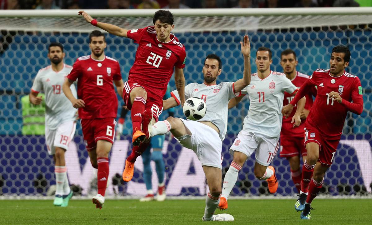 Sardar Azmoun y Sergio Busquets luchan por el balón.