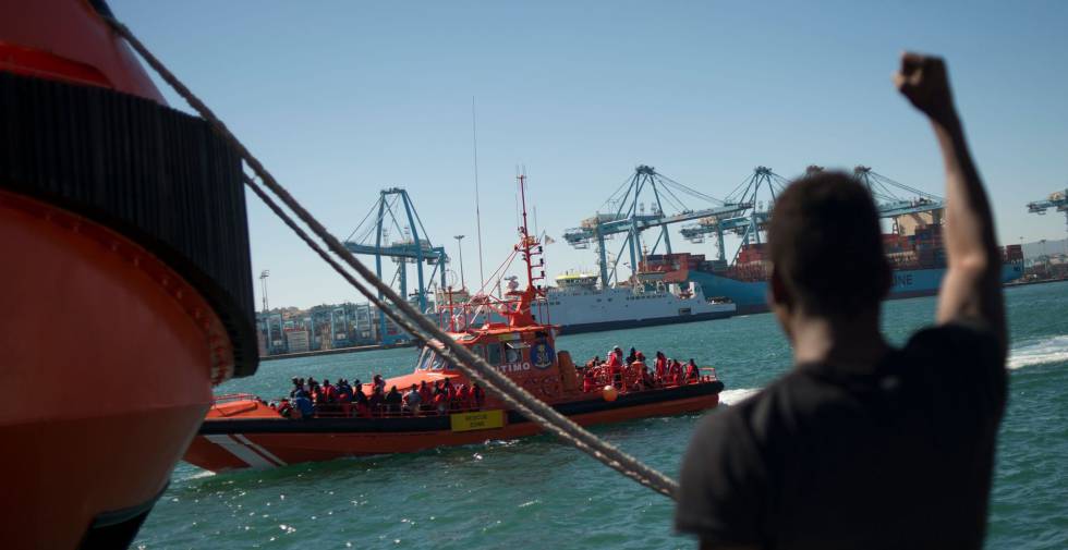 Un hombre saluda en el puerto de Algeciras a unos migrantes recatados en el mar.
