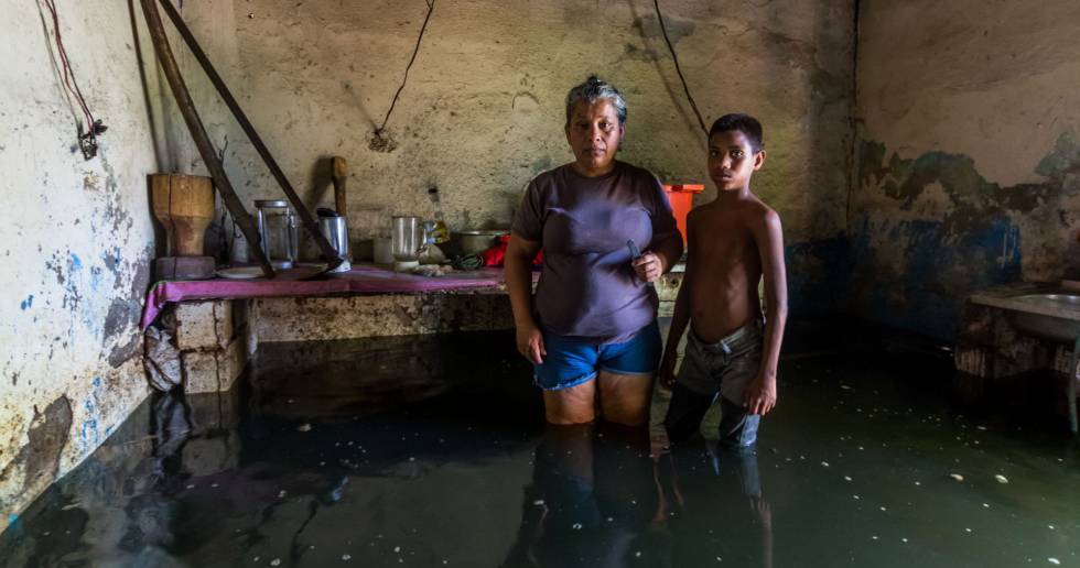 A woman and her son pose inside their flooded house in San Felix, Bolivar state, Venezuela, on August 10, 2018. - The Orinoco river floods have damage houses, crops and generate a potential outbreak to diseases for which medicines are lacking. The floods affect eight states, according to the government. (Photo by William R. Urdaneta AFP)