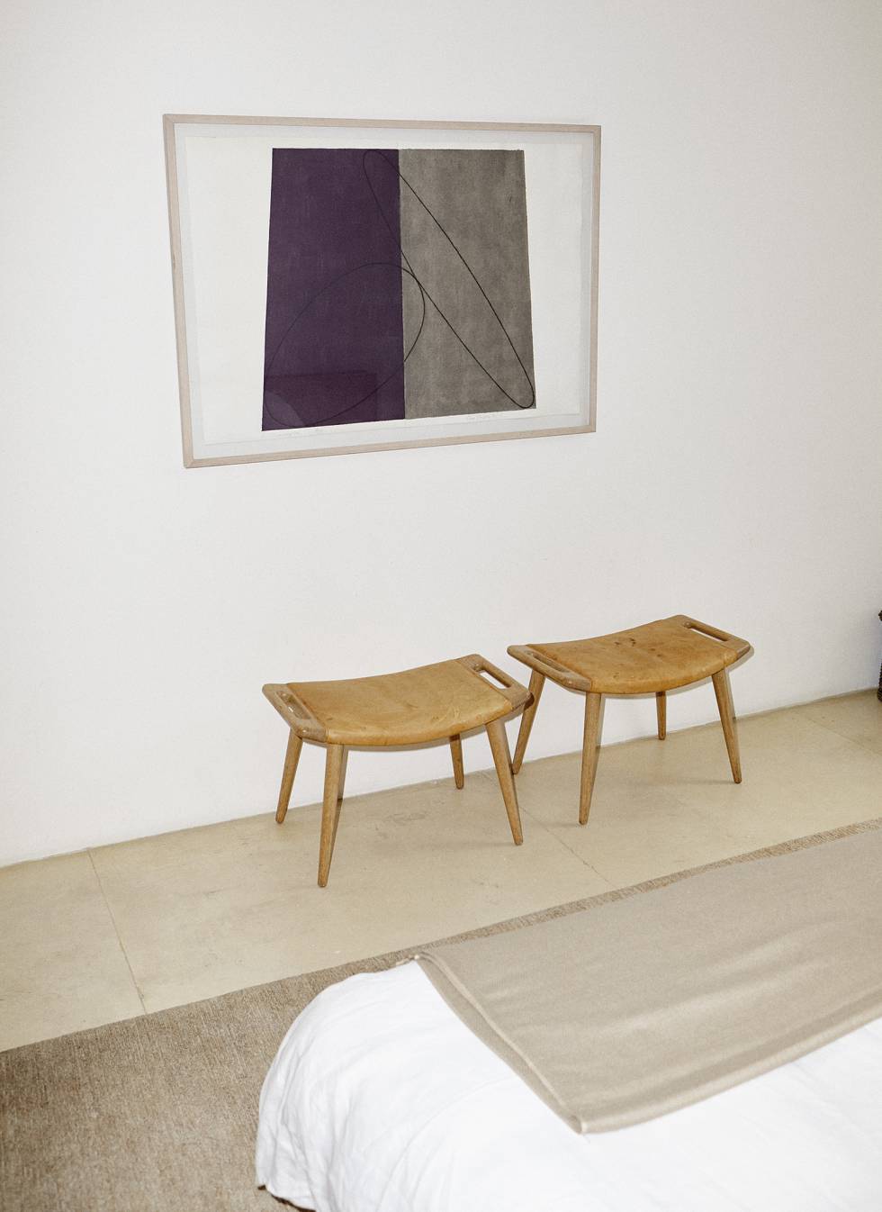 El dormitorio, con dos taburetes de Hans Wegner y un lienzo contemporáneo.