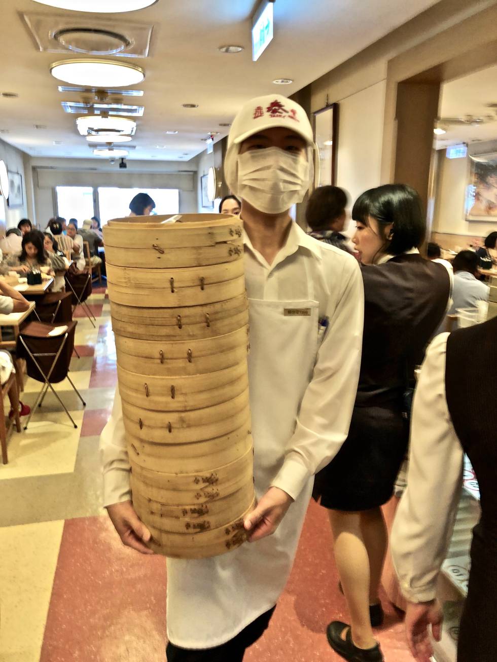 UN CAMARERO CON CESTOS REPLETOS DE XIAO-LONG-BAO CAPEL