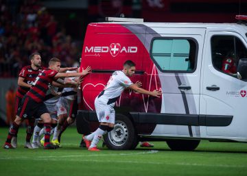 Un grupo de futbolistas empuja una ambulancia para sacarla del campo