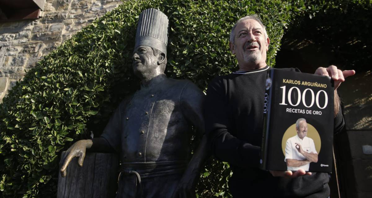 Karlos Arguiñano posa con su último libro junto a una estatua erigida en su nombre en Zarautz (Gipuzkoa).