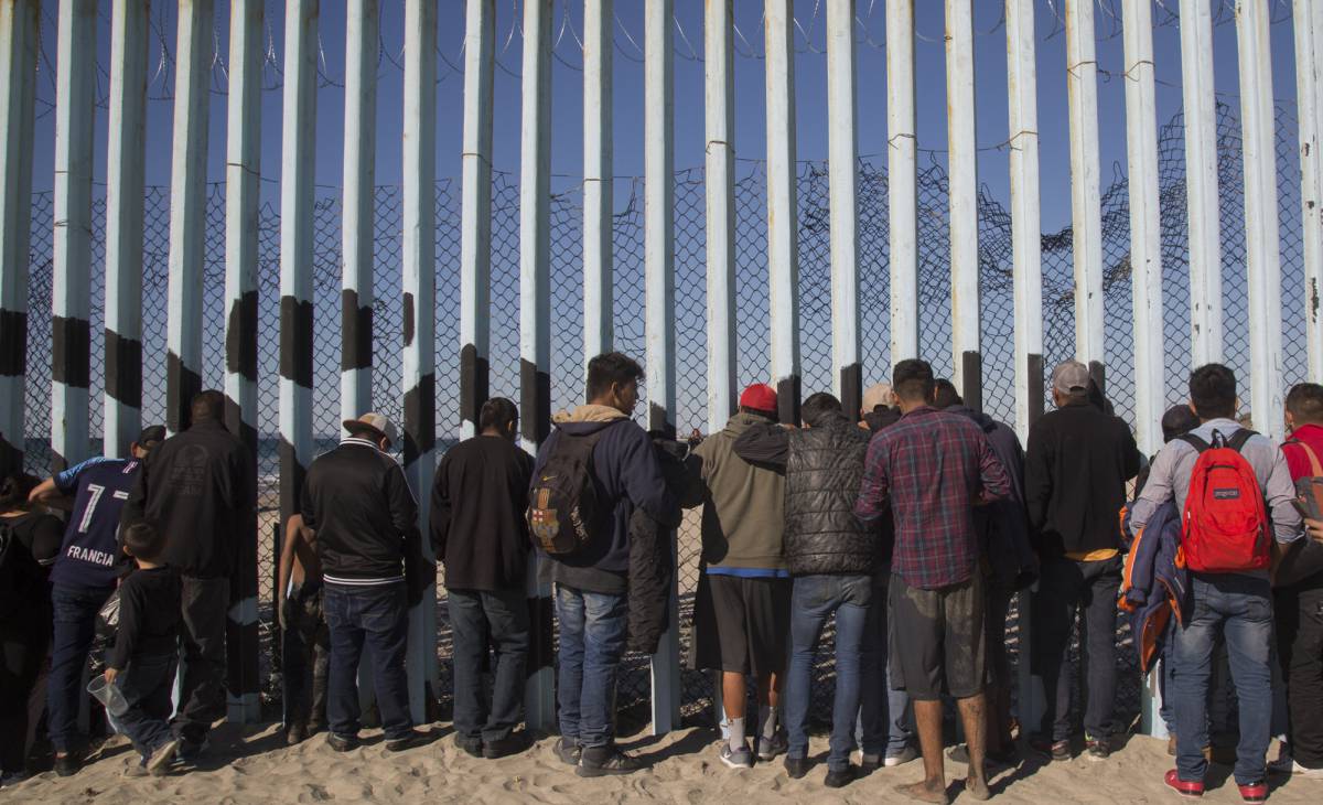 Miembros de la caravana frente a la valla fronteriza en Tijuana.