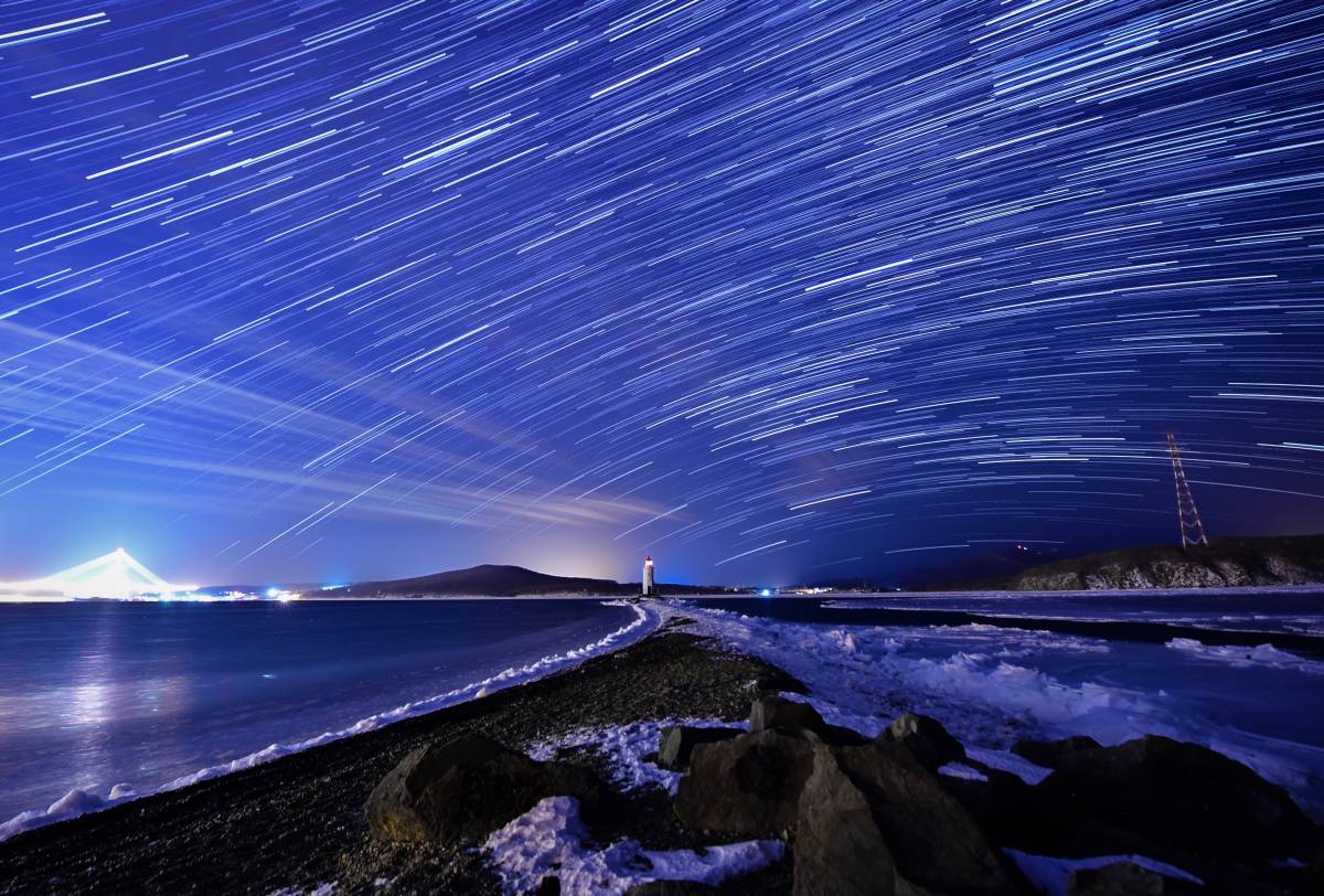 Lluvia de estrellas gemínidas durante su pico, en el cielo nocturno sobre el faro de Tokarevsky en el cabo de Egersheld en la isla de Russky en el mar de Japón.