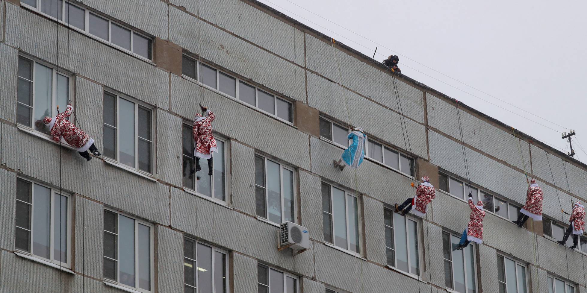 Bomberos rusos vestidos de 'Ded Moroz', el Papá Noel ruso, trepan por la fachada del hospital pediátrico Morozovskaya, en Moscú (Rusia)