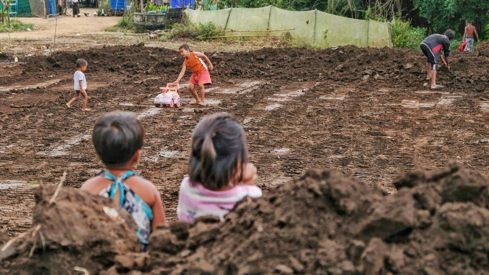 Unos niños de espalda en el campo observan la preparación de una construcción en la zona del vertedero