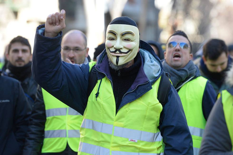 A taxi driver wearing a Guy Fawkes mask and a yellow vest during a strike in Barcelona.