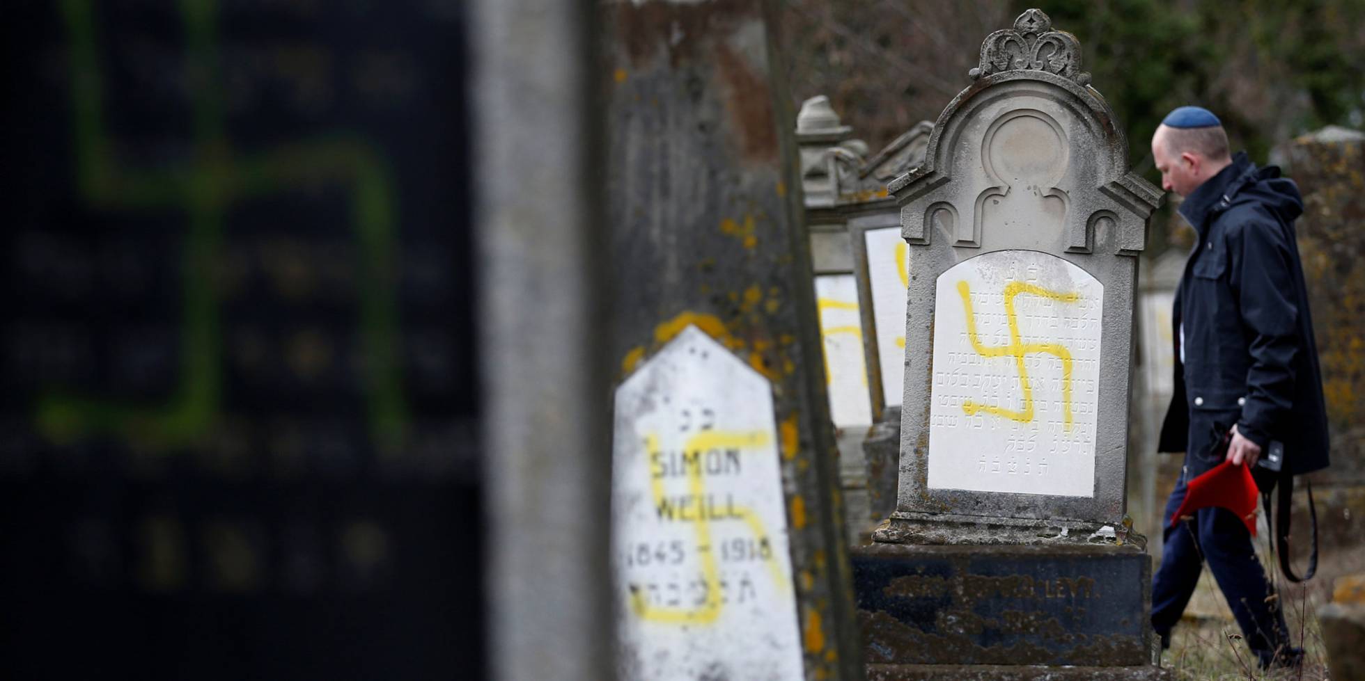 Un hombre camina entre algunas de las tumbas profanadas.