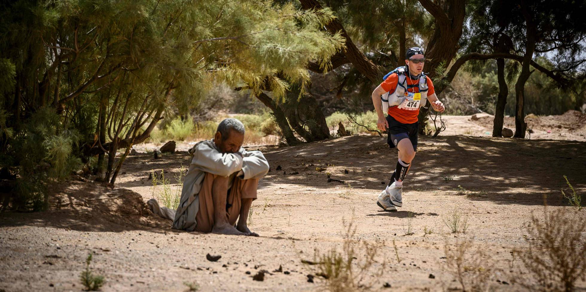 Un competidor pasa junto a un habitante local, durante la etapa 3 de la 34ª edición del 'Marathon des Sables', entre Kourci Dial Zaid y Jebel El Mraïer, en el sur del desierto del Sahara (Marruecos).