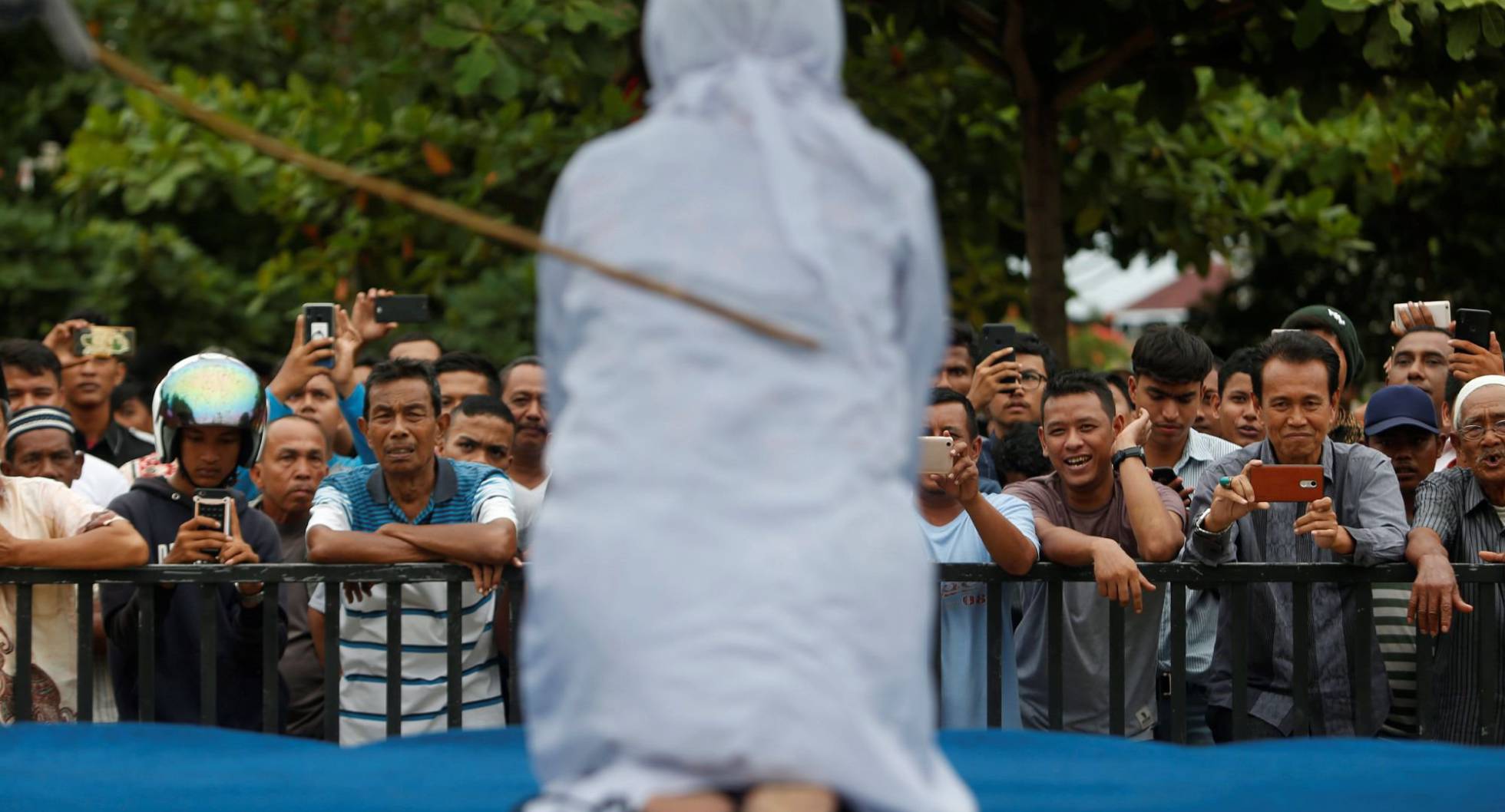 Una multitud de hombres se rien y graban con sus teléfonos móviles como una mujer recibe latigazos en público, acusada de mantener relaciones sexuales fuera del matrimonio en Banda Aceh (Indonesia).