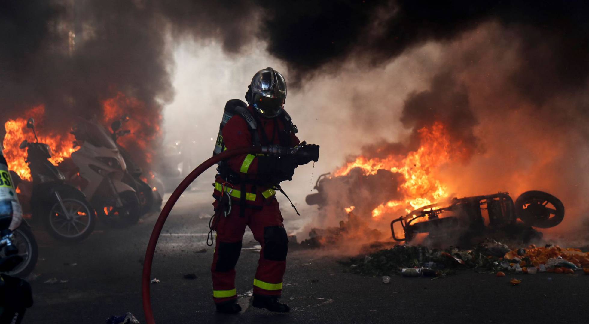Un bombero junto a varias motos ardiendo en París.