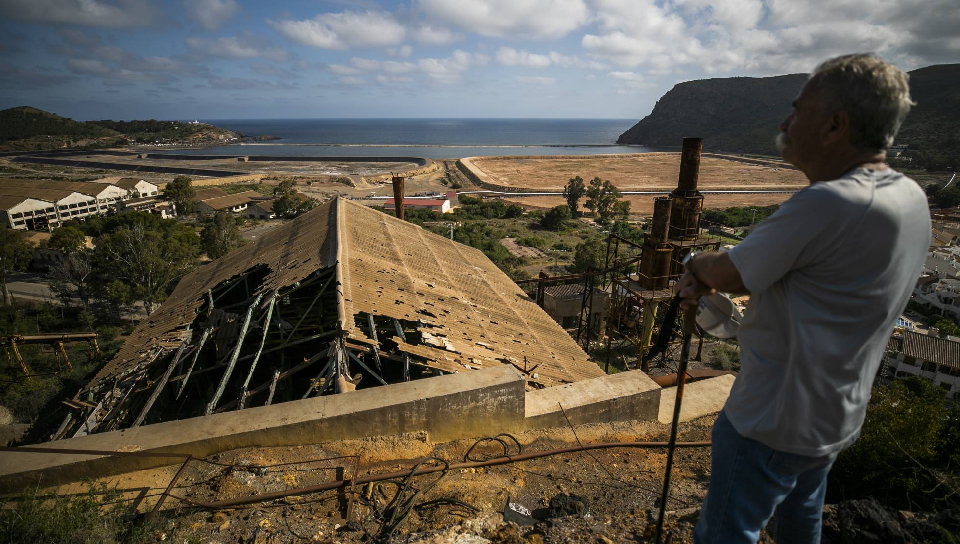 Panorámica de la bahía al fondo, y en primer término, instalaciones abandonadas de la mina de Peñarrolla.
