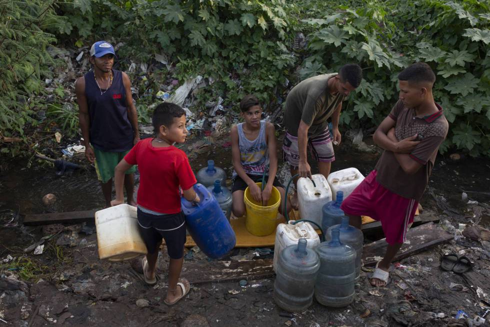 Un grupo de jóvenes se abastece de agua en un riachuelo formado por una tubería rota, el pasado viernes en Maracaibo.