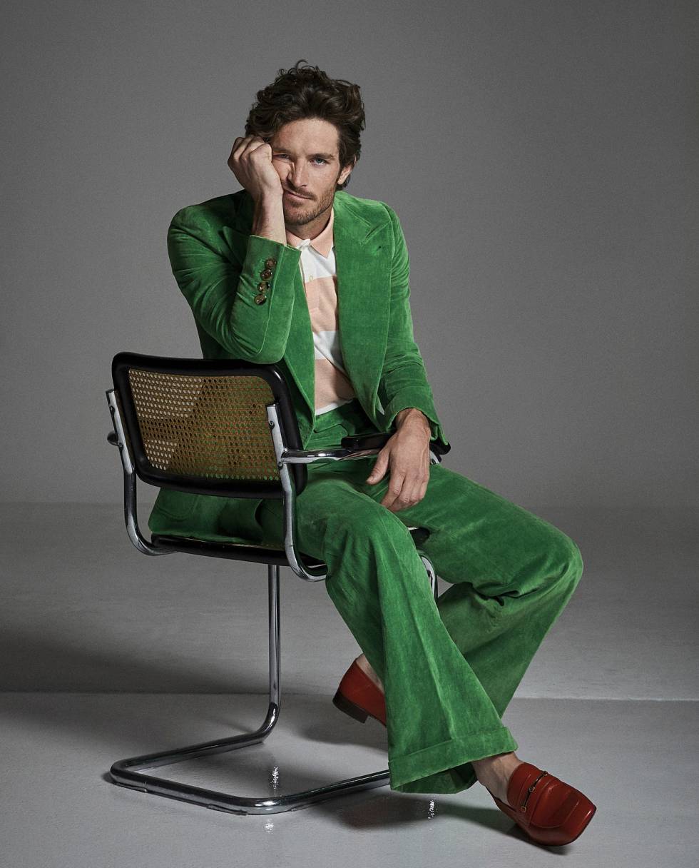 El traje y los mocasines rojos de Justice Joslin son Gucci, y el polo de rugby a rayas, Cortefiel.