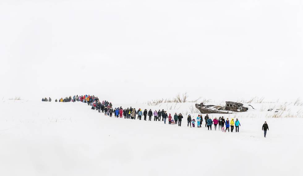El público de la fiesta de los pastores de renos de Dudinka, caminando a lo largo de un río cubierto de nieve.